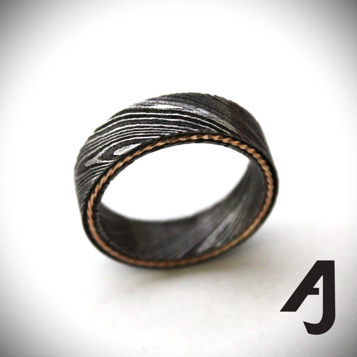 Damascus steel ring with a twisted rose gold inlay, showcasing unique wavy patterns and a blend of rugged durability with elegant warmth