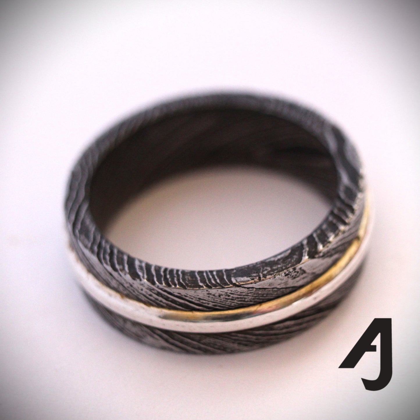 Damascus Silver Spinner Ring with a sterling silver core that spins smoothly within a patterned Damascus steel band, combining fidget-friendly function with bold, handcrafted style.