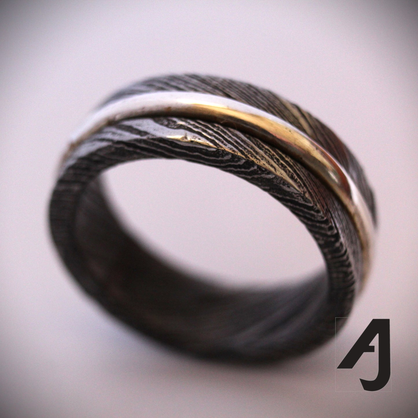 Damascus Silver Spinner Ring with a sterling silver core that spins smoothly within a patterned Damascus steel band, combining fidget-friendly function with bold, handcrafted style.
