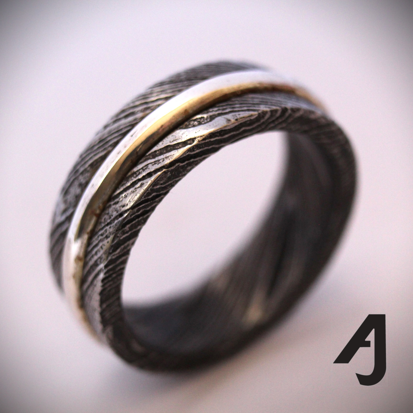 Damascus Silver Spinner Ring with a sterling silver core that spins smoothly within a patterned Damascus steel band, combining fidget-friendly function with bold, handcrafted style.
