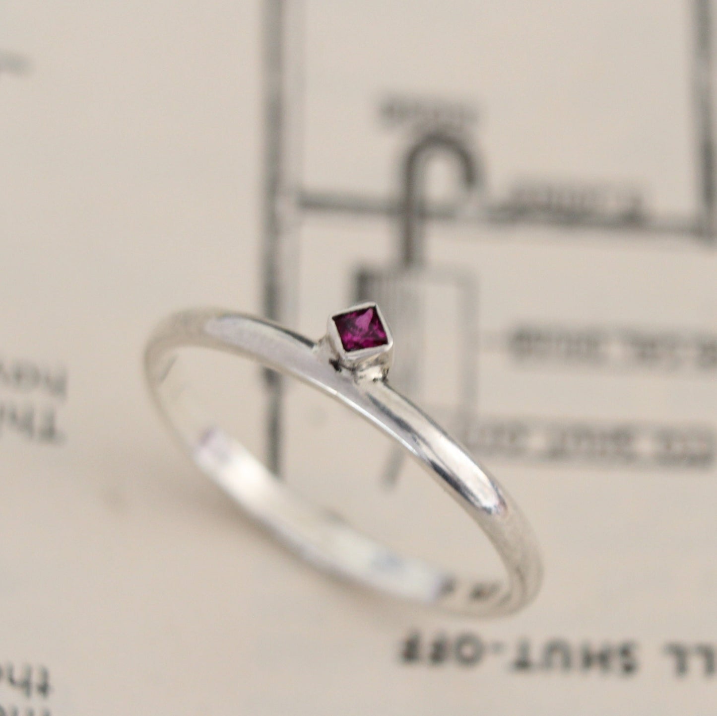 Handmade sterling silver ring with a bezel-set princess-cut ruby, showcasing a blend of modern design and timeless elegance. Thoughtfully crafted with intricate detail, perfect for both everyday wear and special occasions