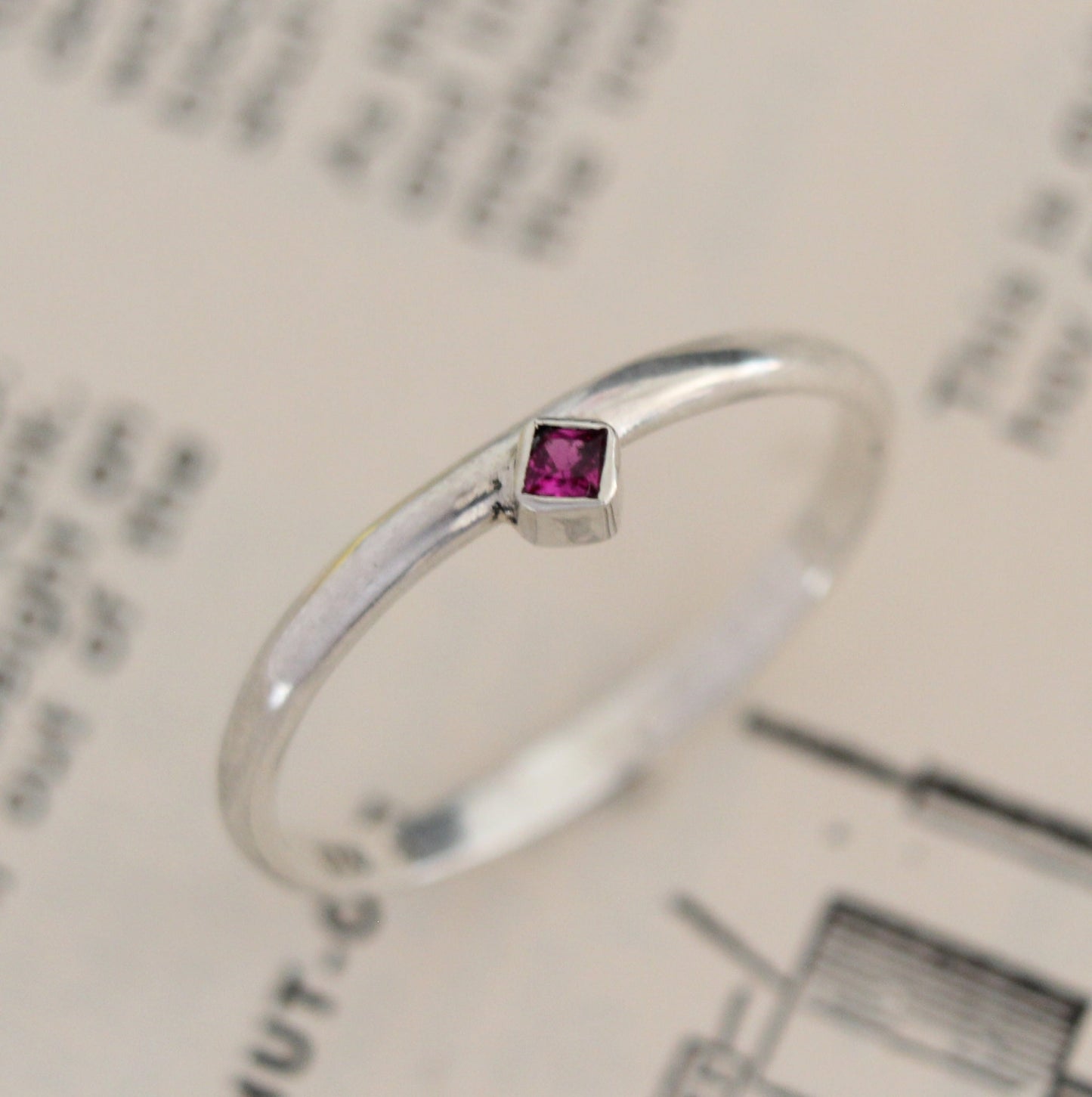 Handmade sterling silver ring with a bezel-set princess-cut ruby, showcasing a blend of modern design and timeless elegance. Thoughtfully crafted with intricate detail, perfect for both everyday wear and special occasions