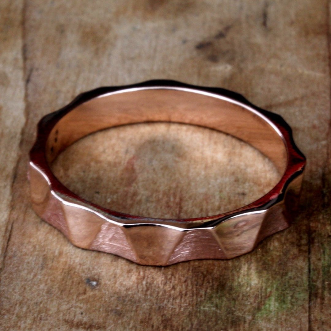18ct rose/pink gold ring with an internally smooth, rounded band for a comfortable fit. The exterior features a dynamic waving angular pattern. The warm pink hue of the rose gold adds elegance, while the modern pattern offers a contemporary touch.