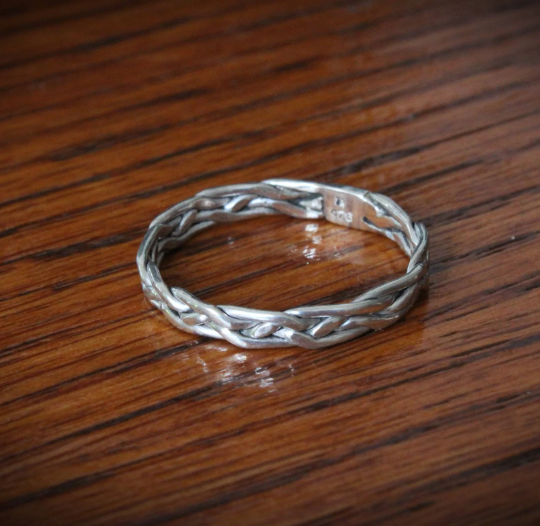 Elegant 'All in Knots' sterling silver Celtic knot ring, featuring a 4-strand braided design. Perfect as a thumb ring, this intricate piece adds a touch of timeless style to any look.