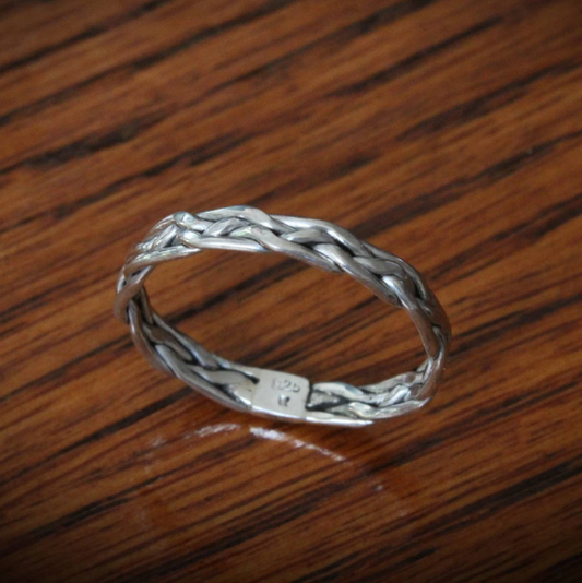 Elegant 'All in Knots' sterling silver Celtic knot ring, featuring a 4-strand braided design. Perfect as a thumb ring, this intricate piece adds a touch of timeless style to any look.