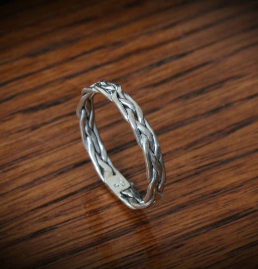 Elegant 'All in Knots' sterling silver Celtic knot ring, featuring a 4-strand braided design. Perfect as a thumb ring, this intricate piece adds a touch of timeless style to any look.