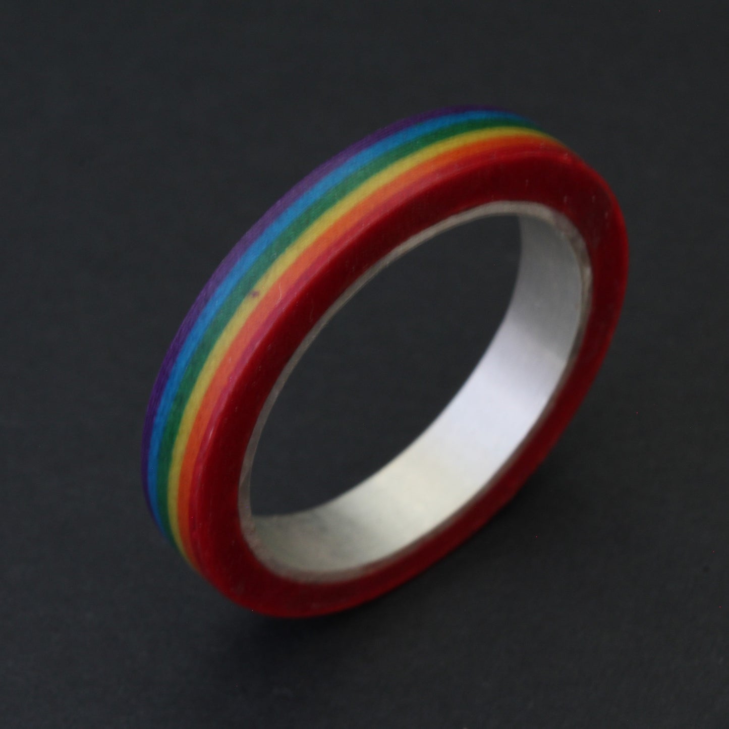 Handcrafted sterling silver band with vibrant LGBTQ+ colours, encased in resin and layered paper, celebrating pride and individuality