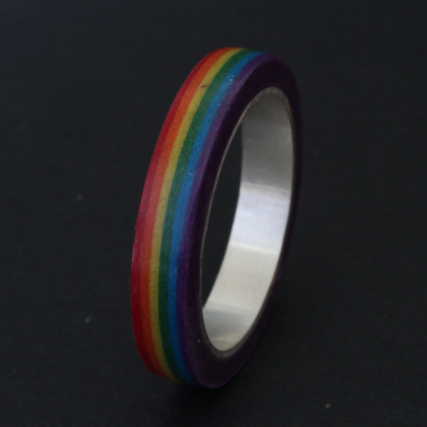 Handcrafted sterling silver band with vibrant LGBTQ+ colours, encased in resin and layered paper, celebrating pride and individuality
