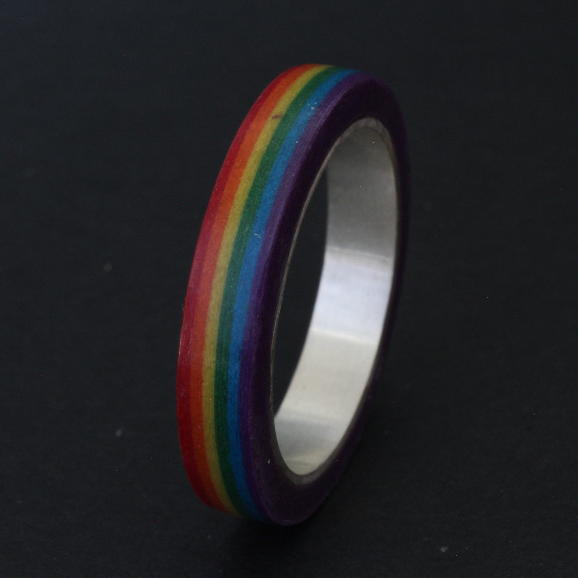 Handcrafted sterling silver band with vibrant LGBTQ+ colours, encased in resin and layered paper, celebrating pride and individuality